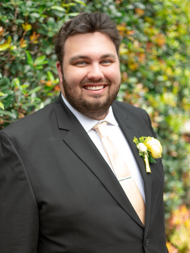 Bibby in a dark suit and tie with a boutonniere